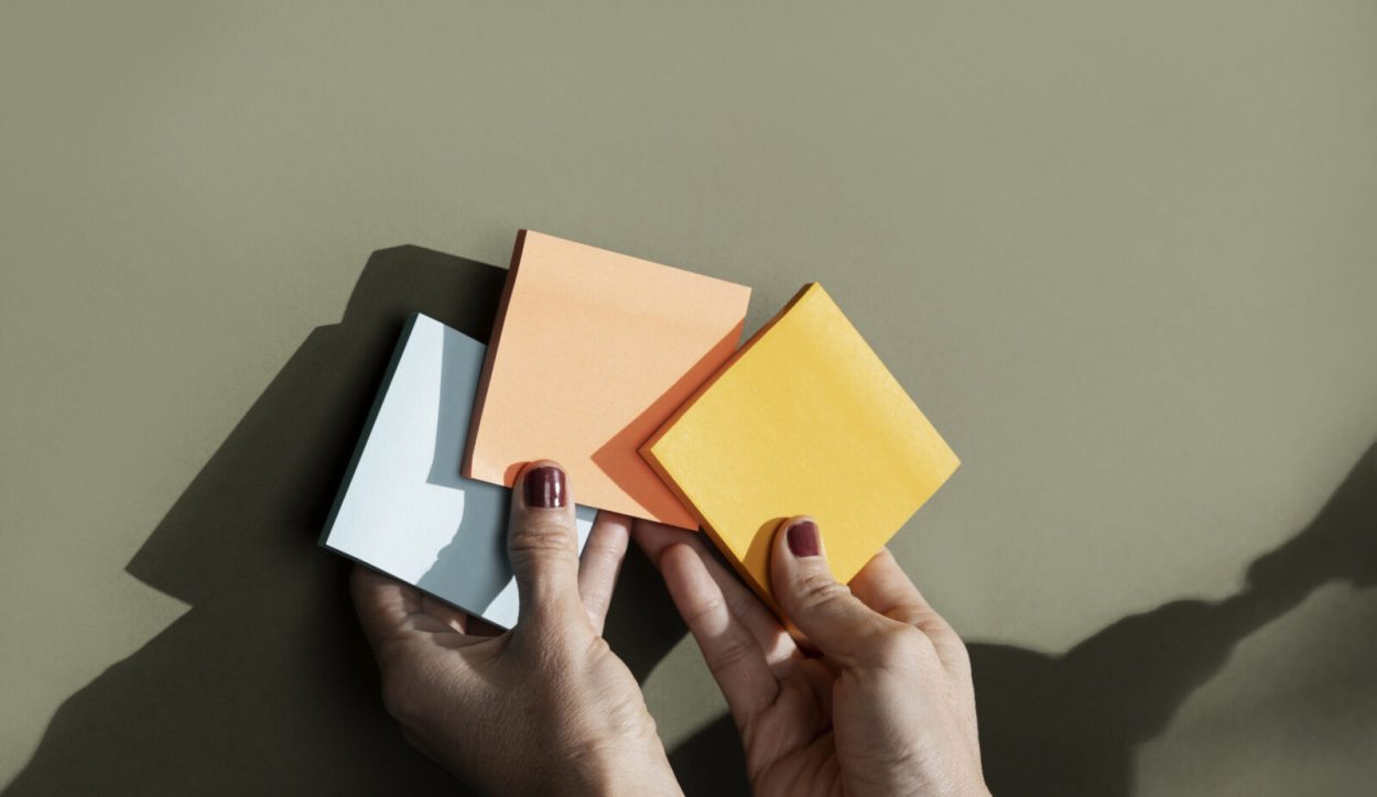 top-view-hands-holding-colorful-post-its